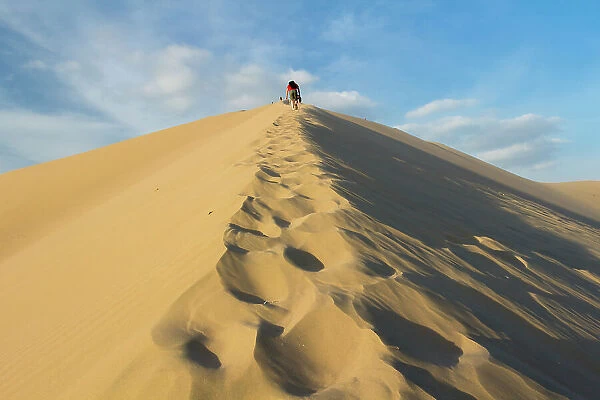 People walking up sand dune, Huacachina, Peru, South America