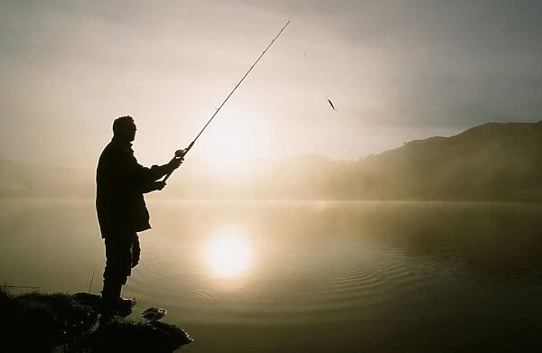 A fisherman on Rydal water at dawn in the Lake district, UK