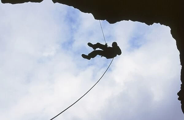A man abseiling in Rydal Cave in the Lake District UK