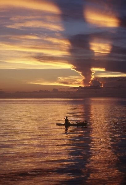 Person in canoe on sunset-orange lagoon. Papua New Guinea