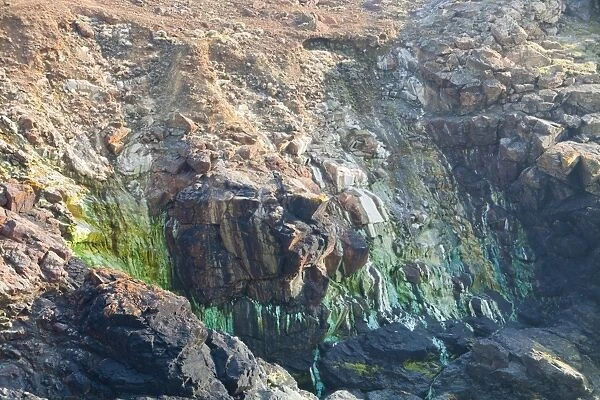 Sea Cliffs stained green from copper deposits leaching from the old Geevor Tin Mine near St Just in Cornwall