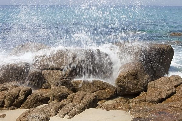 Wave crashing spray over a rock on Porth Nanven beach, Cornwall, UK
