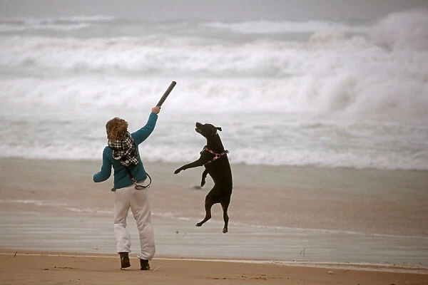 A woman plays with her dog during a storm in Zikim beach