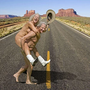 Naked couple wearing cowboy boots and hat crossing road in Monument Valley, Arizona