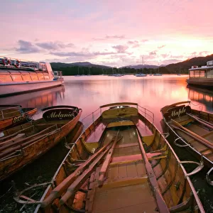Rowing boats at Waterhead Ambleside on Lake Windermere at sunset in the Lake District UK