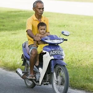 A Tuvaluan man and child on a motorbike on Funafuti atol Tuvalu