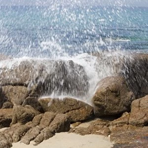 Wave crashing spray over a rock on Porth Nanven beach, Cornwall, UK