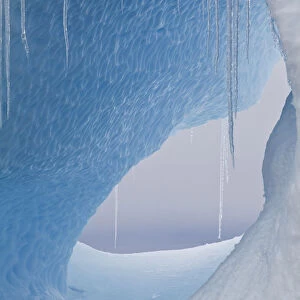 A large hole in an iceberg with icicles hanging. Yalour Islands, Antarctic Peninsula