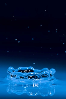 Corona of water splash with many droplets from impact above it Corona of water splash with many droplets from impact above it